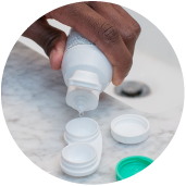 A hand squeezing contact solution into a contact lens case.