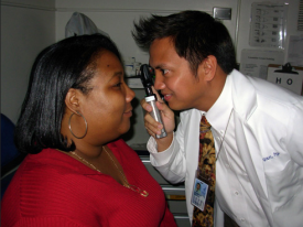 image tagged with patient, lab coat, eye doctor, eye exam, retinoscope, …;