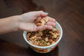 image tagged with holding, bowl, nuts, eating, hold, …;