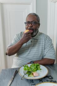 image tagged with greens, sitting, glasses, middle aged, eating, …;