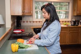 image tagged with glasses, woman, stove, cook, bell pepper, …;