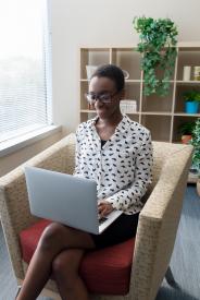 image tagged with african-american, lady, sitting, computer, smiles, …;