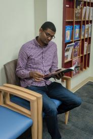 image tagged with african-american, patient, sits, waiting room, reads, …;