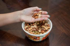 image tagged with hand, eats, bowl, nut, food, …;
