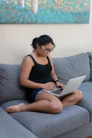image tagged with lady, couch, sits, works, computer, …;