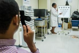 image tagged with woman, african-american, exam, medical care, vision test, …;